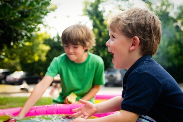 Two boys playing outside in the sun with a colourful water table