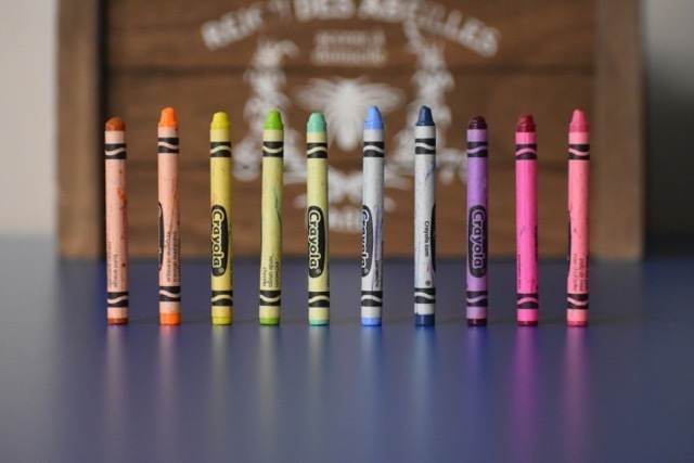 A line of colourful crayons standing up on end on a desk