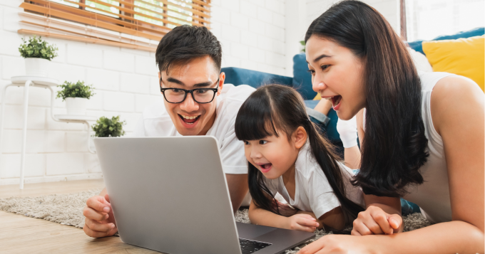Happy parents look at a laptop with their child