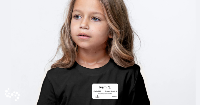 A child in a black t shirt with a white label with name allergies pickup instructions date