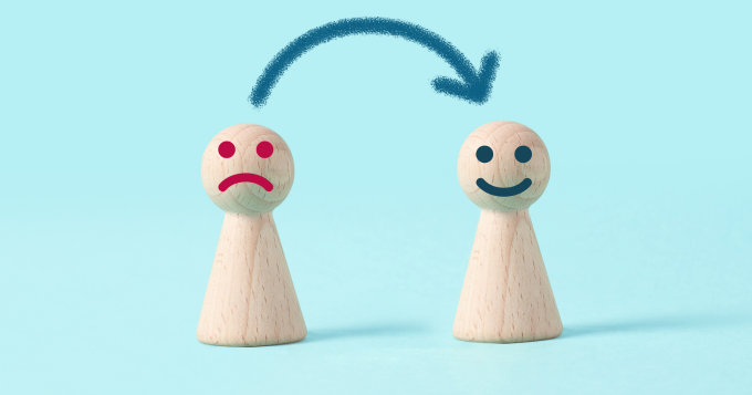 Two wooden characters one with a red frown and one with a blue smile