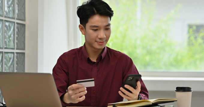A young man enters his credit card data into his devices