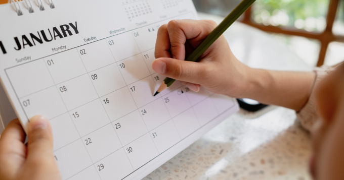 A woman writes in pencil on a Janaury calendar
